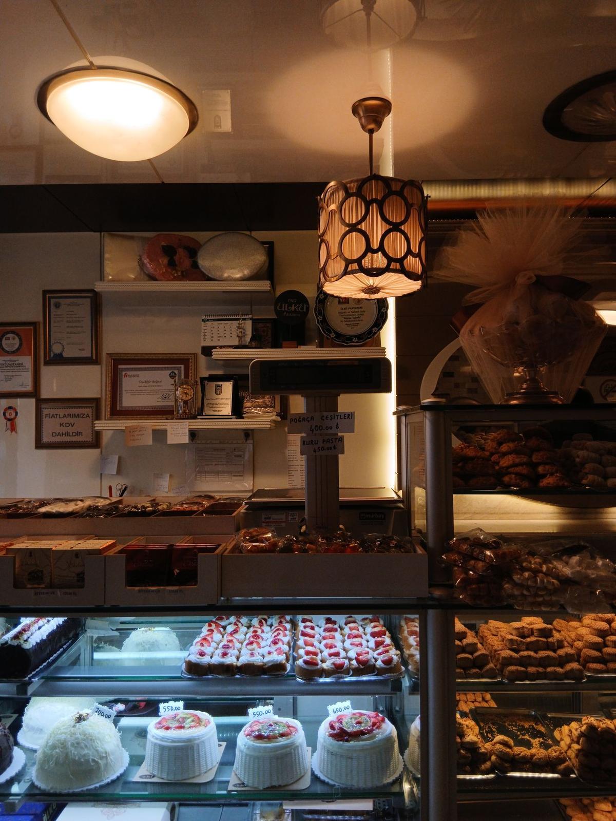 A bakery interior with a display of cakes and pastries